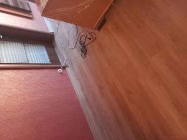 На полу уложено новое покрытие, ровно и аккуратно. Все стыки подогнаны, плинтусы установлены. Обновленный интерьер создает уютную атмосферу в помещении.