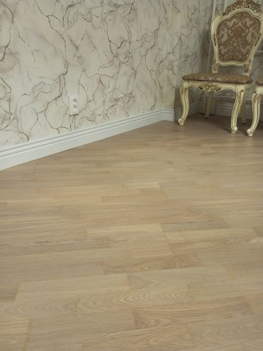 Установлен скрытый плинтус, который гармонично сочетается с паркетом и стенами, создавая аккуратный и завершенный вид интерьера. Работа выполнена качественно, без видимых дефектов.