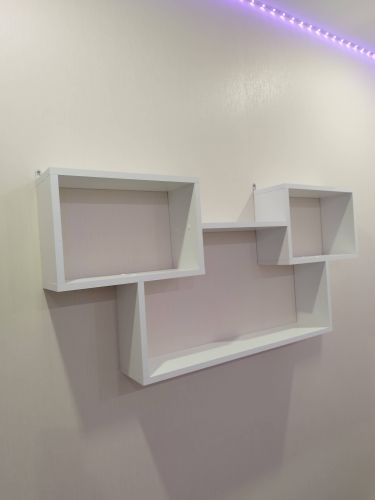 На стене закреплена белая полка сложной формы. Установлены крепления, обеспечивающие устойчивость и надежность конструкции. Работа завершена аккуратно и профессионально.