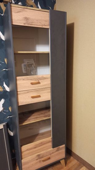 Собран шкаф с полками, ящиками и дверцами. Установлены ручки, закреплены ножки. Все элементы соединены, конструкция устойчива и готова к использованию.