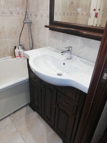 Изображен установленный новый смеситель на раковине в ванной комнате. Работа завершена, сантехника подключена, водопроводные трубы закреплены, герметизация выполнена.