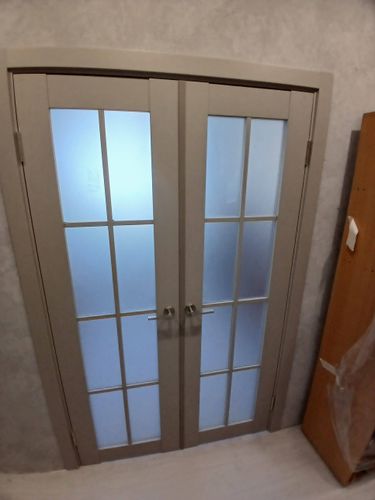 Установлена двустворчатая конструкция с матовыми стеклами и металлическими ручками. Проведена регулировка петель, монтаж наличников и проверка плавности закрытия.