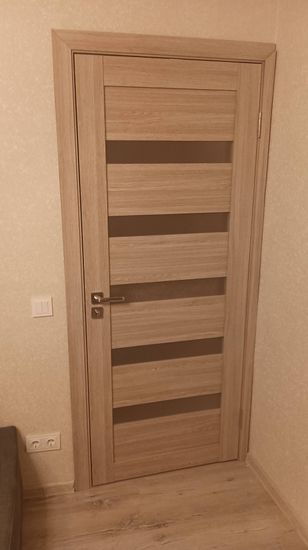 В деревянной двери выполнено отверстие, установлена фурнитура, закреплена ручка, проверена работа механизма. Все элементы подогнаны, обеспечена плавная работа и надежное закрытие.