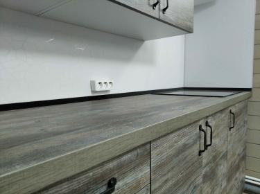 Установлены шкафы, закреплены фасады, смонтирована столешница из ДСП, подключены розетки, навешены ручки, выровнены поверхности, завершена сборка кухонного гарнитура.