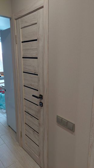 Установлена новая деревянная створка с петлями, ручкой и замком. Проведены работы по креплению коробки, регулировке полотна и проверке функциональности. Завершено оформление проема.