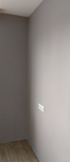 На стену аккуратно наклеены однотонные обои, создающие ровную поверхность. Все швы тщательно выровнены, углы обработаны. Результат — гладкое покрытие без изъянов.