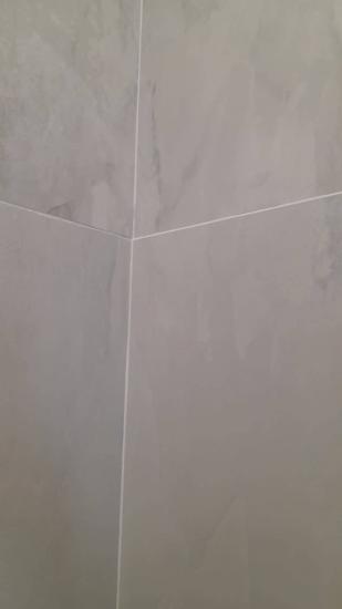 Швы между плитками аккуратно заполнены, поверхность ровная, без изъянов. Цвет затирки гармонирует с облицовкой, создавая единый стиль. Работа завершена, результат эстетичен и долговечен.