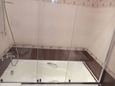 Установлена стальная ванна, подключены смеситель и душ, закреплены стеклянные перегородки, герметизированы швы, проверена система слива, выровнены поверхности, завершена отделка плиткой.