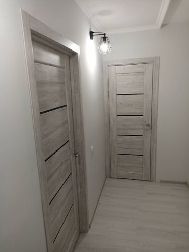 Установлена новая деревянная створка, закреплены петли, врезан замок, отрегулирована фурнитура. Проведена подгонка полотна в проем, обеспечена плавность открывания. Завершена отделка наличниками.