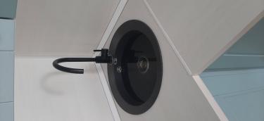 Выполнен монтаж ДСП-поверхности на кухне, установлена круглая раковина с черным смесителем. Все элементы аккуратно подогнаны, обеспечивая ровные стыки и функциональность.