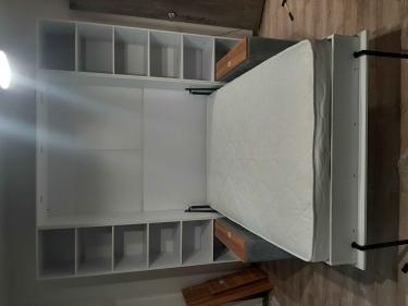 Собрана конструкция с полками, установлено основание, закреплены боковые панели, уложен матрас. Все элементы надежно соединены, обеспечивая устойчивость и функциональность.