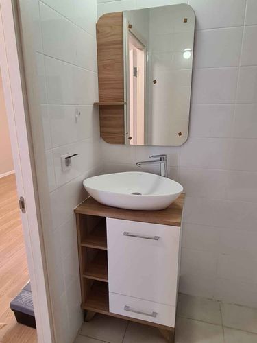 Зеркало аккуратно закреплено на стене ванной комнаты, рядом с раковиной. Установлены крепления, обеспечивающие надежность и безопасность. Завершено оформление интерьера.