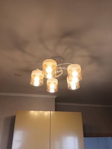 Закреплена новая люстра на натяжной поверхности, подключены провода, проверена работоспособность, установлены лампы, обеспечена надежная фиксация, завершены все монтажные действия.