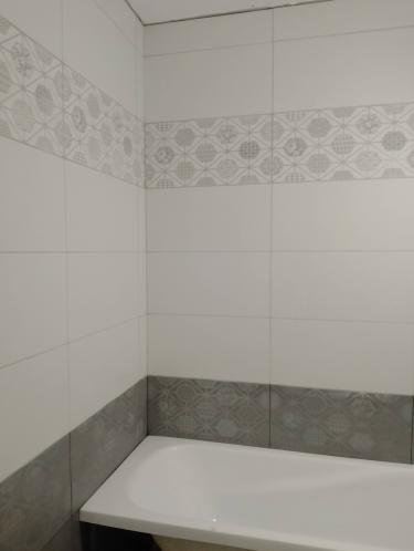 На стенах ванной комнаты уложен керамогранит с геометрическим узором, создающим стильный акцент. Плитка ровно выровнена, швы аккуратно заделаны, поверхность выглядит гладкой и эстетичной.