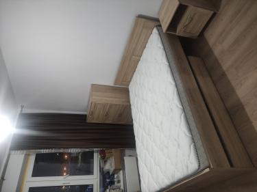 Собран новый деревянный шкаф с четырьмя ящиками, установлен в спальне. Все детали надежно закреплены, фасады выровнены, ручки прикручены, обеспечена функциональность и эстетика.