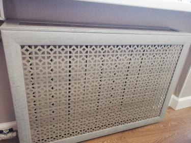 Декоративная панель установлена на отопительный прибор. Конструкция закреплена, закрывает радиатор, гармонирует с интерьером. Эстетичное решение завершено, обеспечивая безопасность и стиль.