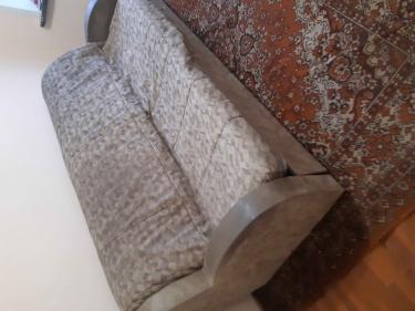 Собран диван: установлены каркас, подлокотники, спинка и сиденье. Проверена устойчивость конструкции, закреплены все элементы. Готов к использованию, стоит на ковре.