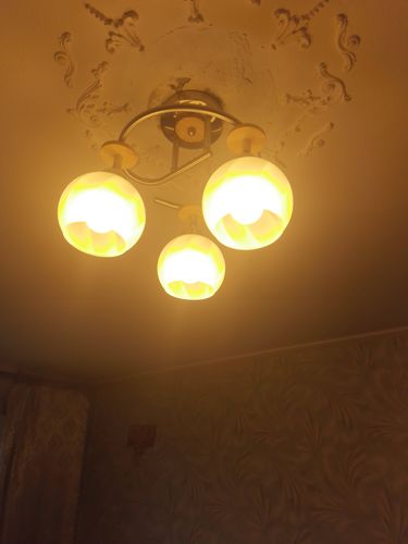 Люстра закреплена на потолке с использованием декоративной розетки. Подключение электропроводки выполнено аккуратно, светильник надежно зафиксирован, обеспечивая равномерное освещение комнаты.