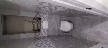 Установлен подвесной унитаз с инсталляцией, выполнена облицовка стен плиткой с геометрическим узором, подключены коммуникации, смонтирована кнопка смыва.