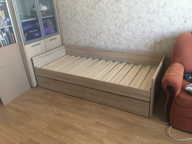 Собрана деревянная конструкция с ламелями, установлены боковые панели, закреплены ящики для хранения, проверена устойчивость, обеспечена надежность соединений, завершена сборка.