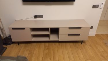 Собрана современная тумба с двумя выдвижными ящиками и открытыми полками. Установлены ручки, прикреплены ножки, выровнена конструкция, обеспечена устойчивость и функциональность.