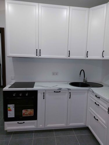 Установлены шкафы, смонтирована столешница, врезана мойка, подключена варочная панель и духовой шкаф. Все элементы аккуратно выровнены и закреплены, обеспечивая функциональность и стиль.