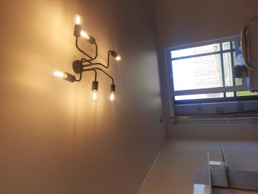 На потолке закреплено осветительное устройство с несколькими лампами. Все элементы установлены и подключены, обеспечивая равномерное освещение в комнате.