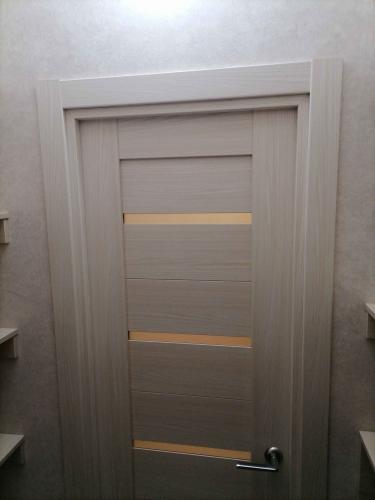 Установлена светлая межкомнатная дверь с горизонтальными вставками, выполнена подгонка коробки, закреплены наличники, врезана ручка, обеспечено плавное открывание и закрывание.