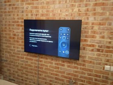 Закреплены опоры для кабельного лотка на кирпичной стене. Установлена телевизионная панель, подключены провода. Работа завершена, оборудование надежно зафиксировано и готово к использованию.