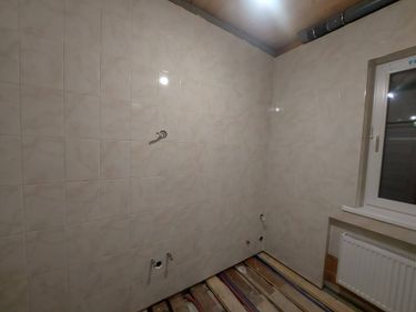 На стенах ровно уложена светлая плитка, создавая аккуратный и гармоничный вид. Все швы тщательно заделаны, обеспечивая прочность и долговечность покрытия.