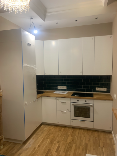 Белоснежные панели аккуратно подогнаны и установлены на кухонные шкафы, создавая современный и стильный вид. Завершенная работа демонстрирует точность и качество исполнения.