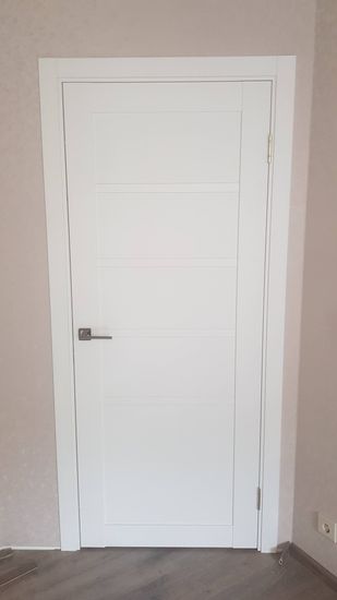 Установлена белая дверь с ручкой и петлями, выполнена регулировка, проверена плавность открывания и закрывания, закреплены наличники, обеспечена герметичность и звукоизоляция.