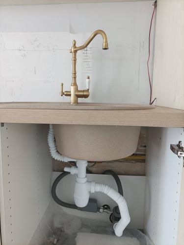 Изображение демонстрирует завершённую установку новой розетки с подведением электричества под раковиной. Провода аккуратно проложены, обеспечивая безопасное подключение.