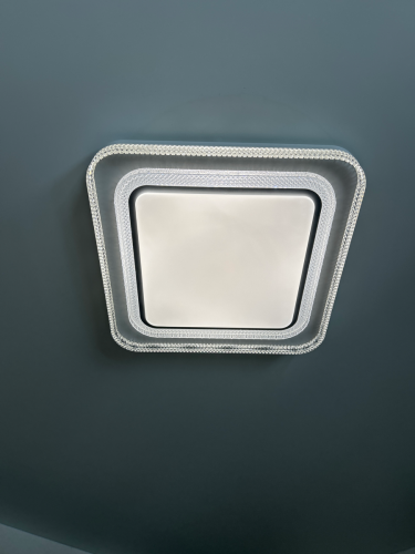 Установлен квадратный потолочный светильник с люминесцентными лампами. Надежно закреплен, подключен к электросети, обеспечивает равномерное освещение. Завершена проверка работоспособности.