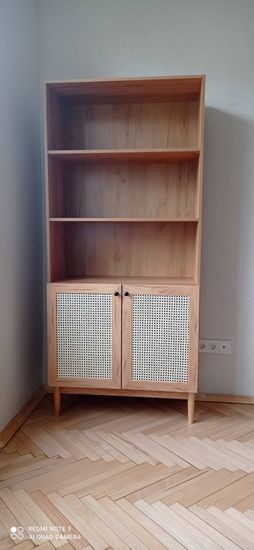 Собран деревянный стеллаж с тремя полками и двумя дверцами. Установлены ножки, закреплены все элементы, обеспечена устойчивость и функциональность конструкции.