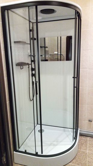 Установлена современная душевая кабина с прозрачными дверями, поддон закреплён, подключены водопровод и слив, обновлены плиточные стены, добавлены полки для удобства.