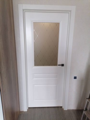 Установлена белая дверь с остеклением, врезаны петли, закреплён наличник, смонтирована ручка, отрегулирована створка, обеспечена плавная работа, завершены отделочные работы.