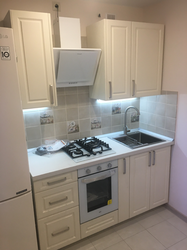 Установлены шкафы, закреплена столешница, подключены плита и мойка, смонтирована вытяжка, выполнена укладка плитки на фартук, установлены светильники под шкафами.