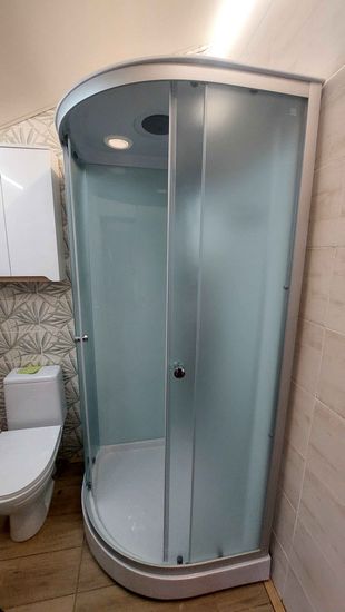 Установлена новая душевая конструкция: закреплены стеклянные панели, смонтирован поддон, подключены водопроводные коммуникации, проверена герметичность соединений, установлены двери.