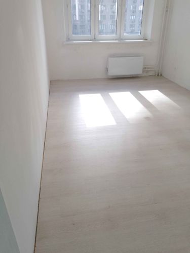 Уложено новое покрытие, ровно и аккуратно, без зазоров. Светлый оттенок придаёт комнате свежий вид. Полностью завершён монтаж, обеспечена гладкая поверхность.