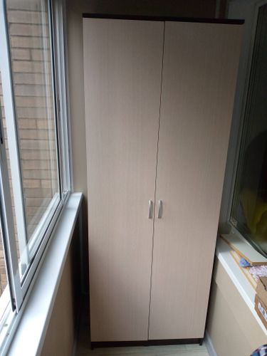 Собран шкаф с двумя дверцами, установлен на балконе. Все элементы надежно закреплены, дверцы ровно висят, ручки прикручены. Работа завершена аккуратно и качественно.