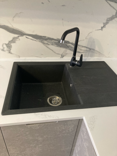 Установлена гладкая поверхность из камня, врезана раковина, смонтирован смеситель. Все элементы надежно закреплены, обеспечивая функциональность и эстетичный вид.