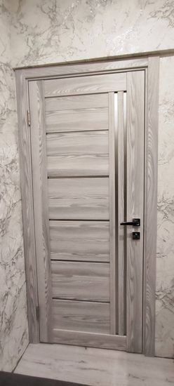 Установлена новая деревянная створка, закреплены петли, врезан замок, отрегулирована фурнитура, проверена плавность закрывания, выполнена отделка наличниками, обеспечена надежность конструкции.