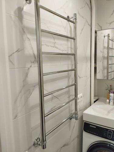 Закреплен новый хромированный полотенцесушитель на стене ванной комнаты, подключен к системе водоснабжения, проверена герметичность соединений, обеспечена функциональность устройства.