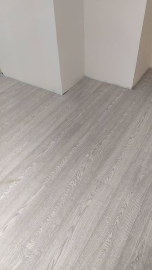 Покрытие пола уложено ровно, без зазоров и складок. Материал аккуратно подогнан к стенам, создавая гладкую поверхность. Завершенный вид подчеркивает текстуру и цвет.