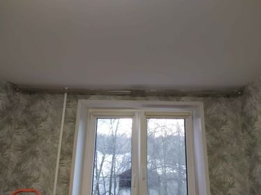 Закреплен металлический карниз на потолке над окном. Установлены крепления, обеспечивающие надежность конструкции. Работа выполнена аккуратно, без видимых повреждений или дефектов.