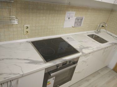 Установлена новая поверхность с вырезами для варочной панели и мойки, идеально подогнана по размерам, обеспечивая функциональность и эстетичный вид кухни.