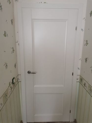 На белой двери аккуратно установлен замок с ручкой. Проведены работы по вырезанию отверстия, закреплению механизма и проверке функциональности. Дверь закрывается плавно и надежно.