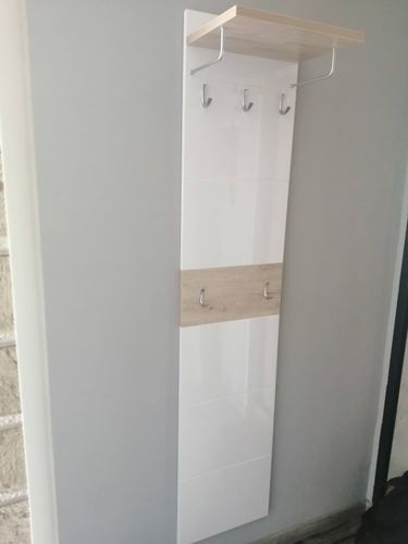 Закреплена настенная панель с крючками и полкой. Установлена конструкция для хранения одежды, обеспечивающая удобство и функциональность в интерьере.