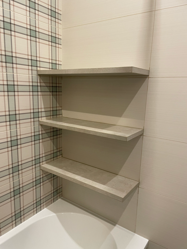Изображение демонстрирует завершённую установку трёх полок в ванной комнате. Полки закреплены на стене с плиткой в клетку, создавая аккуратное и функциональное пространство для хранения.